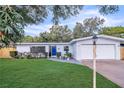 Cozy single-story home featuring a manicured lawn, blue front door, and attached garage at 1384 S Hillcrest Ave, Clearwater, FL 33756