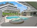 Screened-in pool with a built-in spa and outdoor kitchen area, perfect for relaxation and entertaining guests at 17311 Carriage Way, Odessa, FL 33556