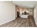 Open-concept living space with wood-look floors and a view of the modern kitchen at 36958 Sagemoor Dr, Zephyrhills, FL 33541
