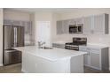 Well-equipped kitchen features stainless appliances, gray cabinets, and a large island with a sink at 36964 Sagemoor Dr, Zephyrhills, FL 33541