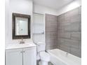 Updated bathroom featuring gray tile, modern fixtures, and a decorative framed mirror at 485 Stillwater Ave, Spring Hill, FL 34606