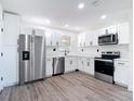 Modern kitchen features stainless steel appliances, white cabinets, and gray wood-look flooring at 485 Stillwater Ave, Spring Hill, FL 34606