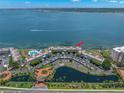 Aerial view of condo complex, pool, parking, gardens, and waterfront with boat; unit marked with red arrow at 5153 Isla Key S Blvd # 415, St Petersburg, FL 33715
