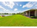A screened-in lanai overlooks the grassy backyard, offering serene pond views and an outdoor seating area at 644 Chipper Dr, Sun City Center, FL 33573