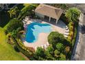 Aerial view of a community pool featuring lounge chairs, mature landscaping, and a covered pavilion for residents at 6677 84Th N Ave, Pinellas Park, FL 33781