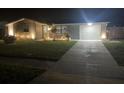 Well-lit front yard showcasing a single-story home with driveway and manicured lawn at night at 1144 Rushmore Dr, Holiday, FL 34690
