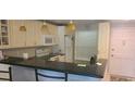Bright kitchen featuring sleek black countertops, tile backsplash, and modern appliances under pendant lighting at 12760 Indian Rocks Rd # 1049, Largo, FL 33774