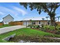Single-story home featuring a metal roof, attached garage, lush landscaping, and a well-manicured lawn at 2306 41St E St, Bradenton, FL 34208