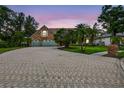 Charming brick home featuring a paved driveway, lush lawn, and mature trees at twilight at 3269 Nicks Pl, Clearwater, FL 33761