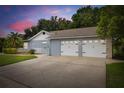 Spacious two-car garage with white doors and adjacent landscaping featuring a white picket fence at 3501 Sarazen Dr, New Port Richey, FL 34655