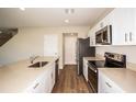 Modern kitchen boasting white cabinets, stainless steel appliances, and wood-look floors at 36933 Sagemoor Dr, Zephyrhills, FL 33541