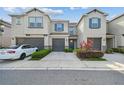 A charming two-story townhome featuring a gray garage, blue shutters, and inviting landscaping at 6825 Citrus Creek Ln, Tampa, FL 33625