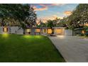 Twilight view of a cozy home with a well-maintained lawn and a long driveway leading up to the property at 7003 Yule Ln, Tampa, FL 33637