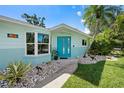 Inviting front exterior with a blue door, stone accents, and lush landscaping at 709 Pinewood Dr, Dunedin, FL 34698