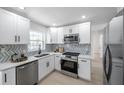 Well-lit kitchen featuring stainless steel appliances, white cabinets, and modern backsplash at 8045 Colton Dr, Port Richey, FL 34668