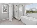 Elegant bathroom featuring a freestanding tub, glass enclosed shower, and bright windows at 8050 Praise Dr, Tampa, FL 33625
