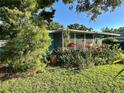 Landscaped yard showcases the exterior of this single story home with screened in porch at 1605 Logan St, Clearwater, FL 33755