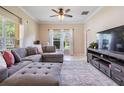 Open living room with large windows, a gray sectional, and a stylish entertainment center at 20302 Noble Oak Pl, Tampa, FL 33647