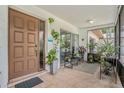 Inviting covered front porch with tiled flooring, plants, and a decorative front door at 2270 Spruce Ln # B, Palm Harbor, FL 34684