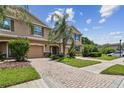 Beautiful townhome exterior with a brick driveway, lush landscaping, and a well-maintained lawn at 26835 Juniper Bay Dr, Wesley Chapel, FL 33544