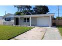 Single-story home with a driveway leading to an attached garage and a green lawn at 3150 Beacon Square Dr, Holiday, FL 34691