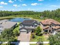 Aerial view of a beautiful house with a brick driveway, lush landscaping, and a serene lake backdrop at 3477 Barbour Trl, Odessa, FL 33556