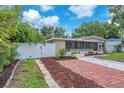 A cozy home featuring a brick driveway, white fence, and a lovely screened-in porch at 4731 W Leila Ave, Tampa, FL 33616