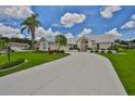 Expansive property with a long driveway leading to a light beige house, beautifully adorned with palm trees and verdant landscaping at 602 Deep Lake Ln, Sun City Center, FL 33573