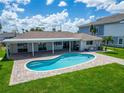 Backyard view showcases the private kidney-shaped pool, well-manicured lawn and covered patio area at 6334 Cocoa Ln, Apollo Beach, FL 33572