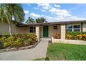 Inviting home entrance with green front door, detailed brick accents, and beautiful, colorful landscaping at 6530 68Th N St, Pinellas Park, FL 33781