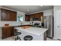 A stylish kitchen featuring dark cabinets, stainless steel appliances, a bright white quartz island, and modern stools at 12824 Wanderlust Pl, Parrish, FL 34219
