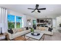 Bright open-concept living room featuring a large window, two couches, modern decor, and seamlessly connected kitchen at 12824 Wanderlust Pl, Parrish, FL 34219