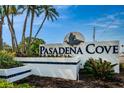 The Pasadena Cove community sign features palm trees, plants and a flying bird statue at 1324 Pasadena S Ave # 501, South Pasadena, FL 33707