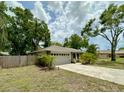 Charming home featuring a two-car garage with a paved driveway surrounded by mature trees and landscaping at 1548 Foxboro Dr, Palm Harbor, FL 34683
