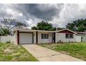Charming home showcasing a white exterior, brown trim, and a spacious driveway at 3025 Palamore Dr, Holiday, FL 34691