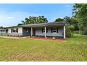 Charming single-story home features a covered porch, red front door, and landscaped front yard at 3212 Cork Rd, Plant City, FL 33565