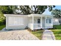 Charming home with a blue front door, white railing, and a walkway through the landscaped front yard at 3907 W Walnut St, Tampa, FL 33607