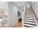 Bright hallway featuring hardwood floors, staircase, bench, and artwork leading to the bedroom at 532 W Plaza Pl # 3, Tampa, FL 33602