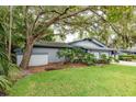 View of the home's exterior showing lush greenery, mature trees and a well-maintained lawn at 60 Birdsong Ct, Oldsmar, FL 34677