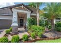 Inviting front porch with brick columns and walkway, complemented by verdant landscaping and palm trees at 9672 Ivory Dr, Ruskin, FL 33573