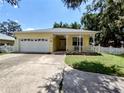 Charming yellow home featuring a welcoming front porch, two-car garage, and well-maintained front yard at 1006 Tropical Dr, Bradenton, FL 34208
