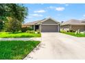 Inviting single-story home with lush green lawn and a paved driveway leading to a two-car garage at 10909 Kirkwall Port Dr, Wimauma, FL 33598