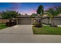 Charming single Gathering home showcasing a well-manicured lawn, palm trees, and a neutral-toned exterior at dusk at 14047 Weddington Ter, Hudson, FL 34669