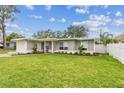 Charming single-story home with a lush green lawn and manicured landscaping under a blue sky at 2452 Bayshore Blvd, Dunedin, FL 34698