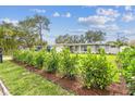 A well maintained front yard with manicured shrubs in front of a gray house under a blue sky at 2452 Bayshore Blvd, Dunedin, FL 34698