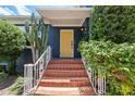 Inviting front entrance showcasing a bright yellow door, red tiled steps, and lush greenery at 2819 N Central Ave, Tampa, FL 33602