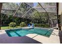 Sparkling screened-in pool area with a shaded area and a serene backyard view at 3353 Wedgewood Way, Tarpon Springs, FL 34688