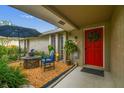 Inviting front porch featuring a seating area and a vibrant red door adorned with a wreath at 5744 Thrush Dr, New Port Richey, FL 34652
