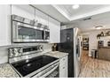 Modern kitchen features stainless steel appliances, white cabinets, and sleek granite countertops at 5744 Thrush Dr, New Port Richey, FL 34652