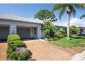 Inviting home exterior showcasing a well-manicured lawn, mature trees, and a convenient attached garage at 8451 Candlewood Rd # 8451, Seminole, FL 33777